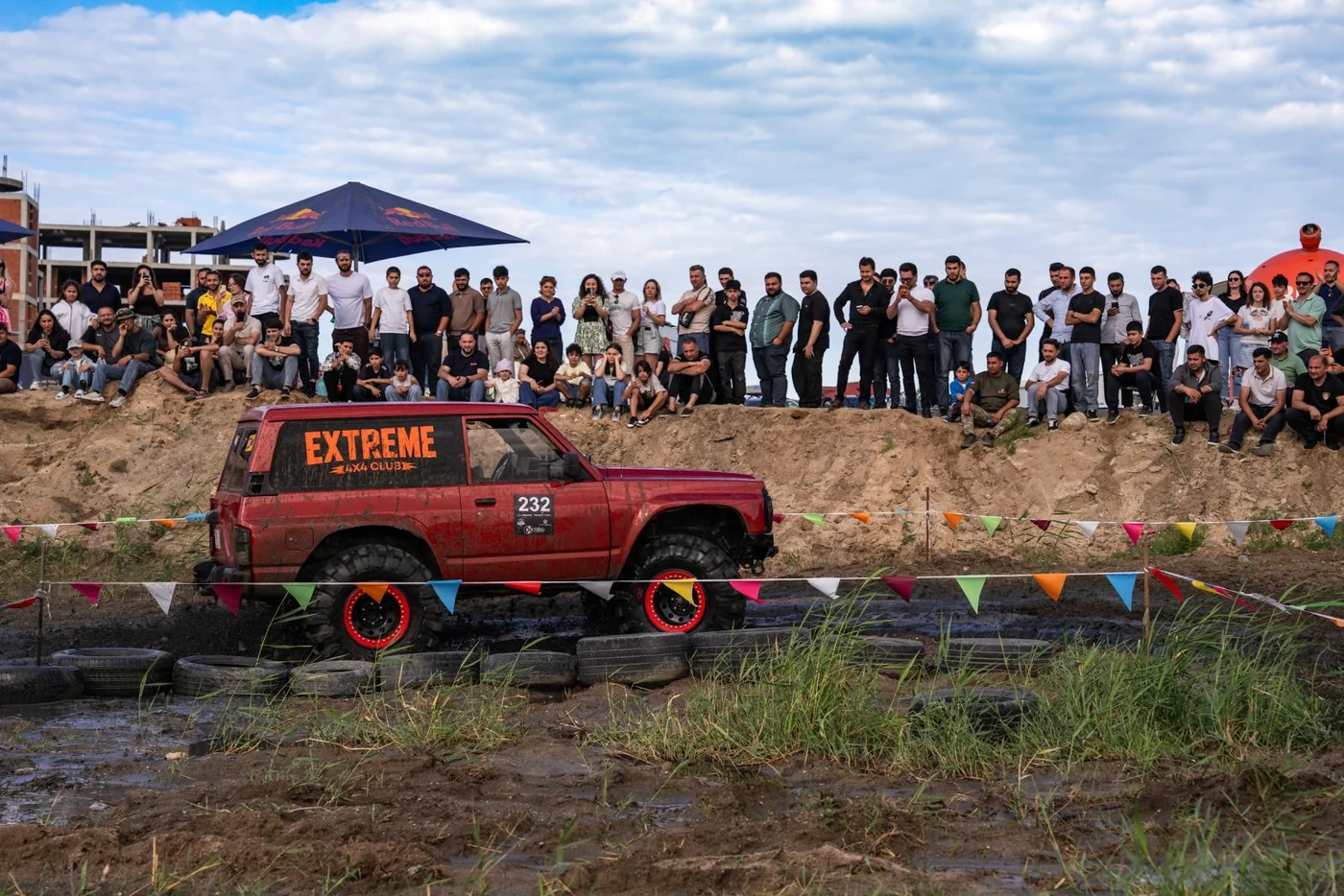 Extreme club's Land Rover No. 232 on the tire section, with spectators on a sand mound